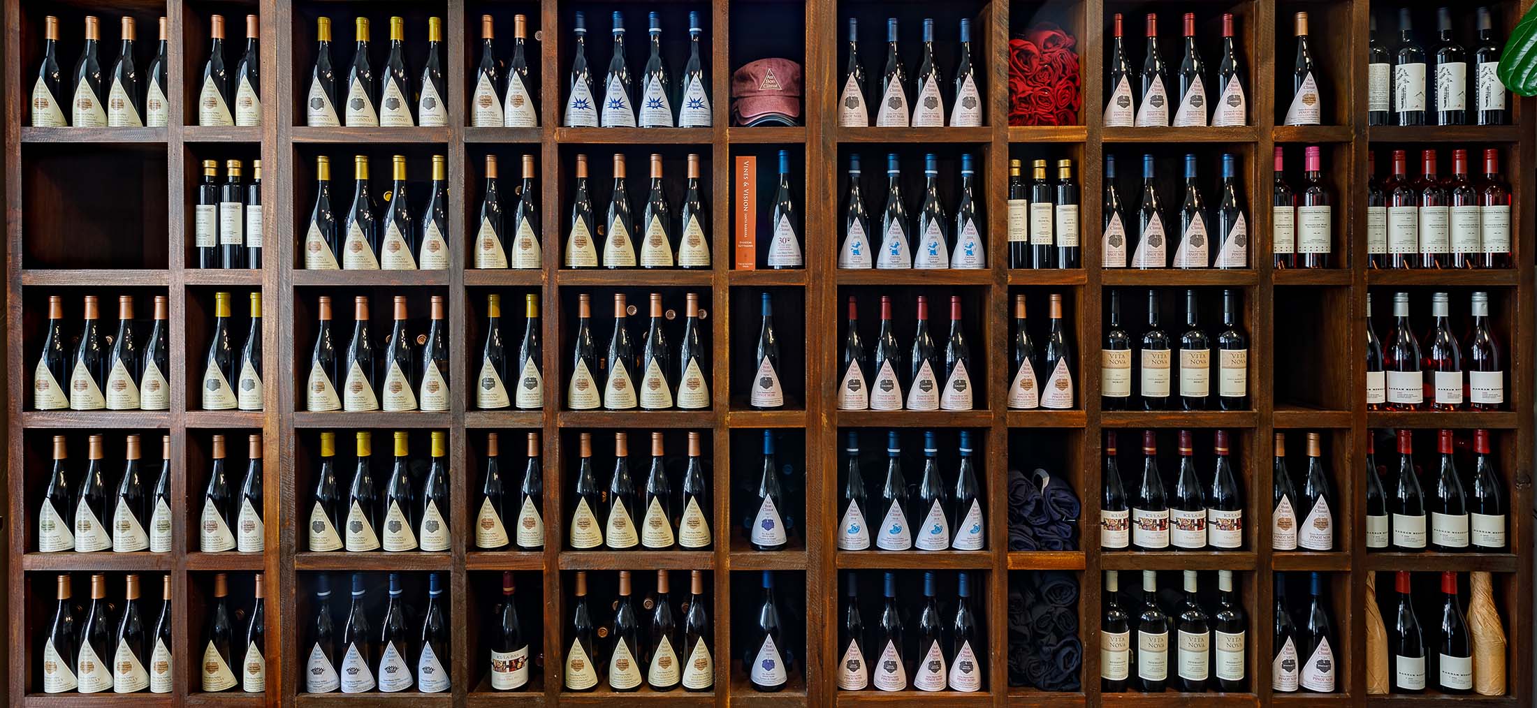 The Library wall of wines at the Au Bon Climat tasting room in Santa Barbara - many shelves full of Au Bon Climat and Clendenen Family Vineyards wine bottles with the labels facing out.